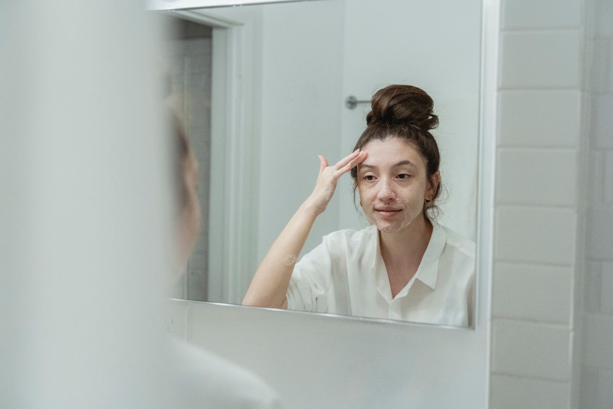 Mujer aplicando un sérum facial frente al espejo
